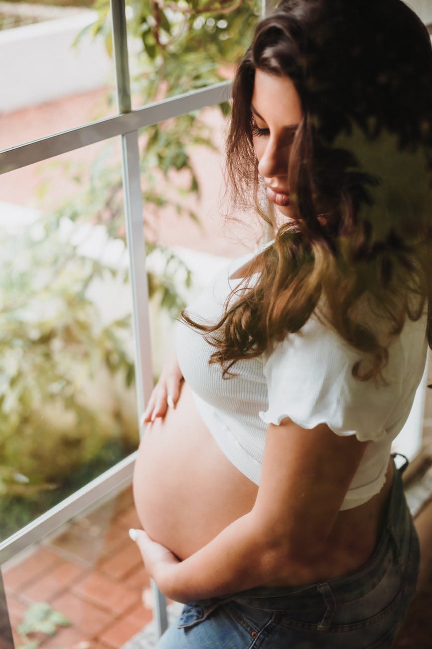 pregnat woman standing next to window